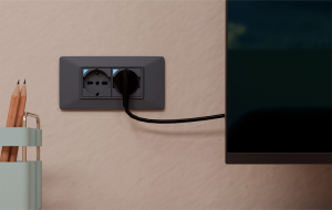 P40 S installata a parete, con spina collegata a un dispositivo elettronico, integrata nel punto presa esistente e compatibile con le serie civili più diffuse.