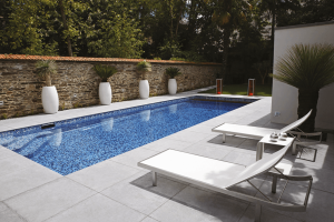Area piscina esterna con lettini, piante e presa da esterno Wide di 4box installata in prossimità dell’acqua.